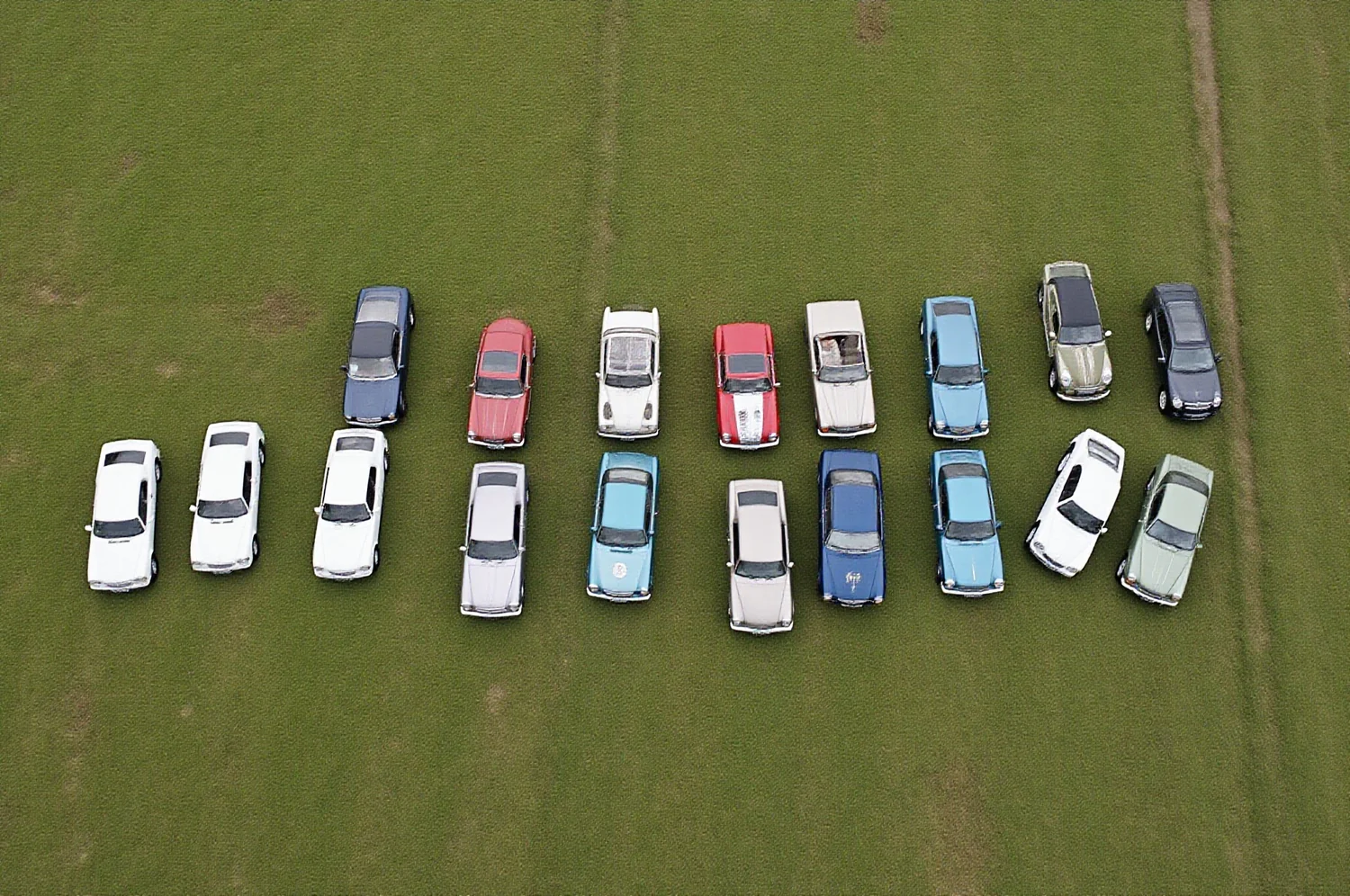 Classic cars parked in rows on mown grass, seen from directly above